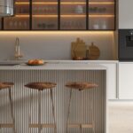 Minimalistic modern kitchen with reeded glass cabinets, fluted kickboard, Caesarstone Mineral Oyster surfaces, stainless steel rangehood and ovens.