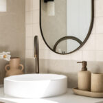 Caesarstone 2141 Snow surface in Minimalist bathroom vanity with oval mirror, round vessel sink, soap dispensers, and striped towel.