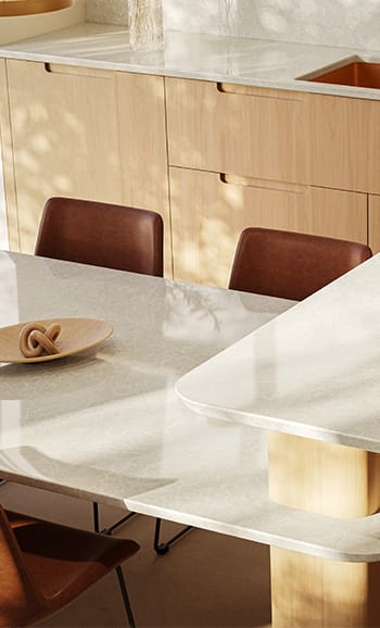 Modern kitchen island benchtop flowing into dining room table, using Caesarstone mineral surfaces.
