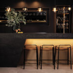 Sophisticated home bar with ambient lighting, featuring a dramatic black Caesarstone mineral surface.