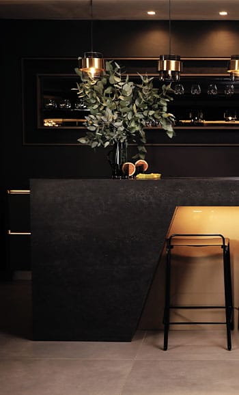 Sophisticated home bar with ambient lighting, featuring a dramatic black Caesarstone mineral surface.