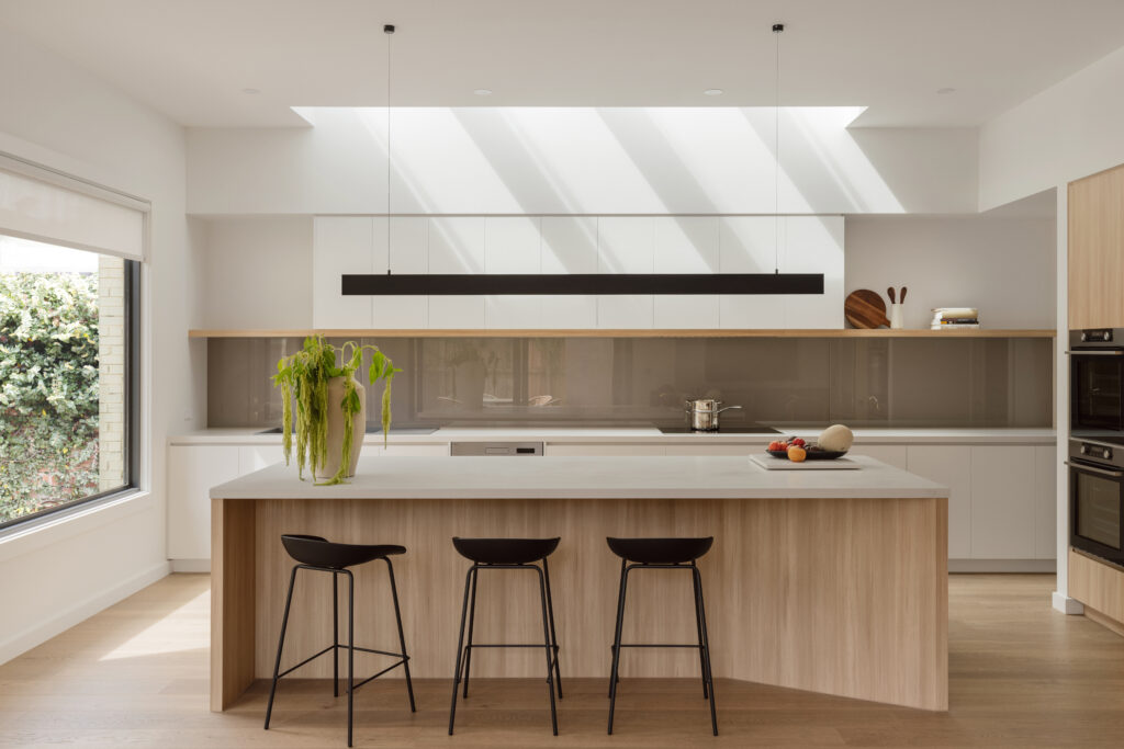 L-shaped kitchen with Caesarstone island benchtop and matching rear surfaces, combining open-plan flow with modern design aesthetics.
