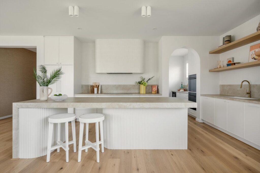 L-shaped kitchen with Caesarstone Porcelain island benchtop and matching rear surfaces, combining open-plan flow with modern design aesthetics.