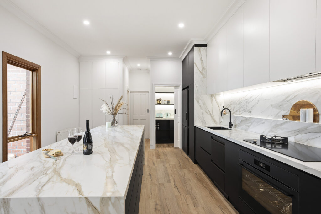 Galley kitchen layout with a Caesarstone Porcelain island bench parallel to rear benchtop and cabinetry, showcasing efficient workflow, premium fixtures and contemporary design.