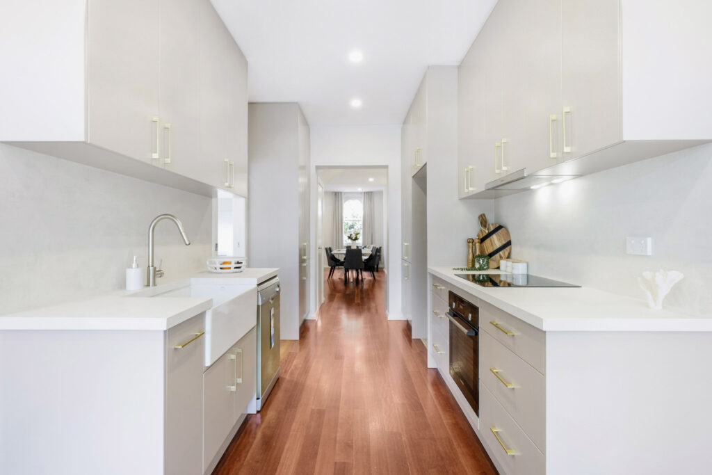 Compact galley kitchen featuring Caesarstone Porcelain benchtops, parallel white cabinetry and sleek modern lighting for efficient design