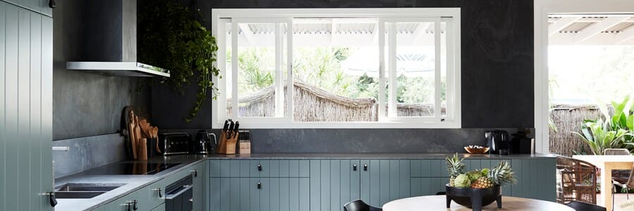Modern caesarstone kitchen with green cabinetry, grey stone splashback, and concrete benchtops.