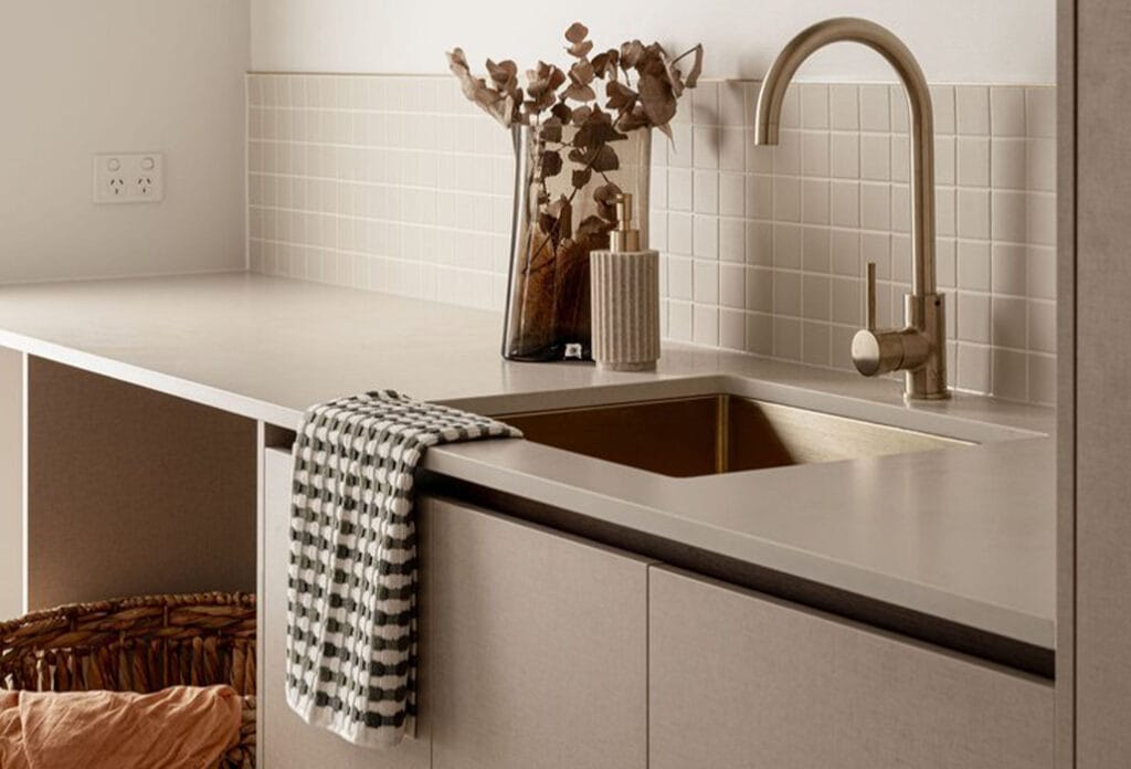Laundry design featuring Caesarstone Adamina Laundry benchtop, tiled splashback desing on a neutral palette