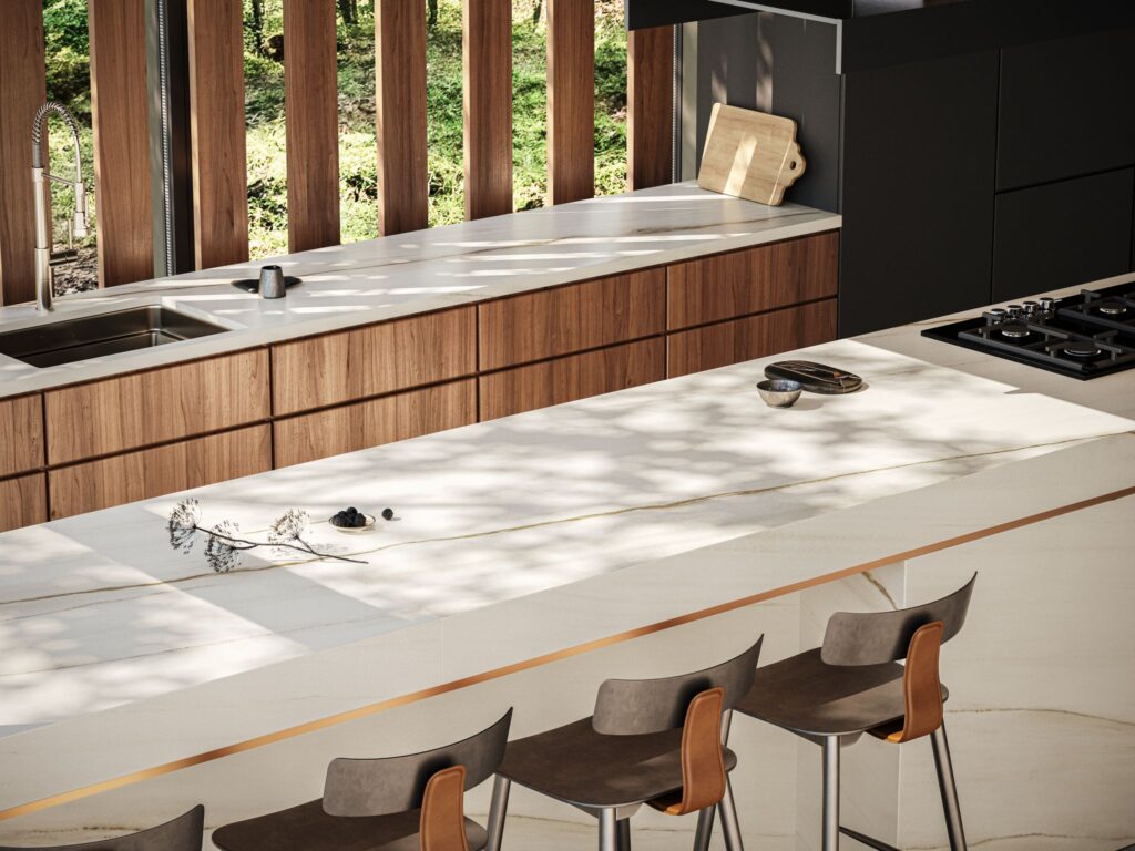 Minimalist kitchen and island benchtop made from white Caesarstone<sup>®</sup> porcelain surfaces, with light airy tones and timber accents.