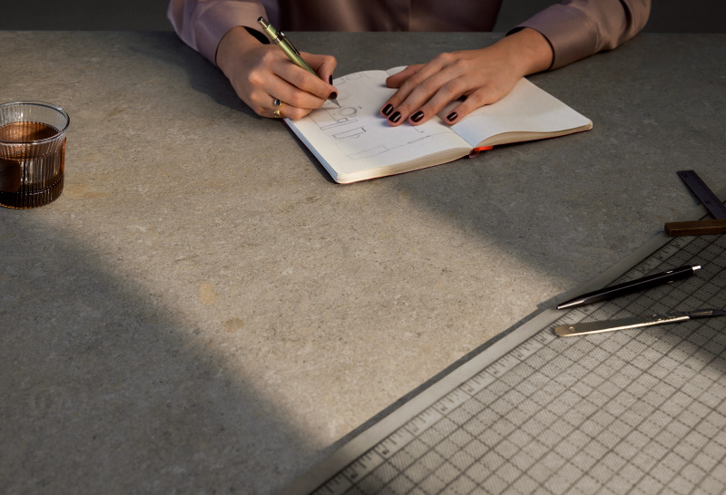 Woman sketching and working at a grey Caesarstone porcelain benchtop