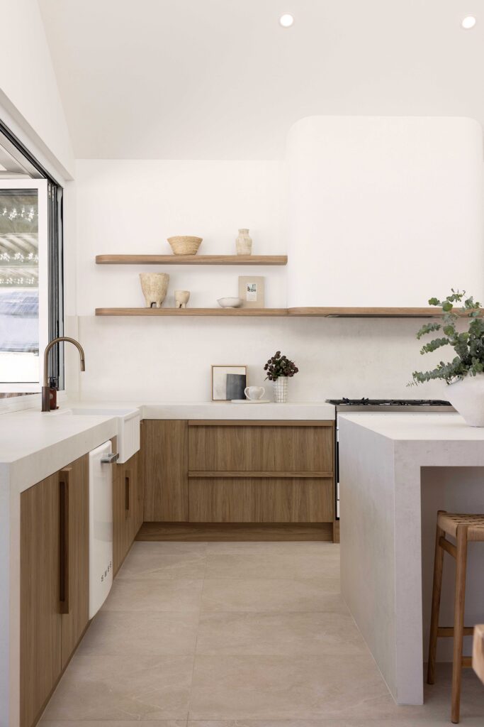 Bright, open-plan kitchen with Caesarstone<sup>®</sup> porcelain surface, featuring a large island and integrated farmhouse sink for a relaxed, coastal feel.
