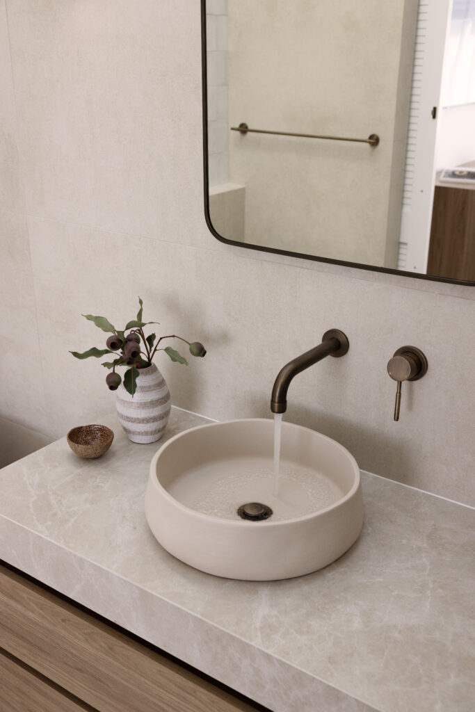 Calming bathroom retreat featuring Caesarstone<sup>®</sup> porcelain surface, paired with warm timber vanities and soft, natural finishes for a spa-inspired feel.