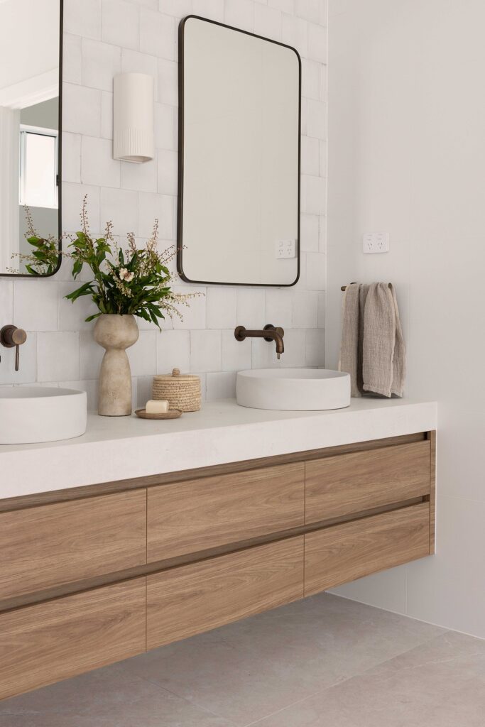 Calming bathroom retreat featuring Caesarstone<sup>®</sup> porcelain surface, paired with warm timber vanities and soft, natural finishes for a spa-inspired feel.