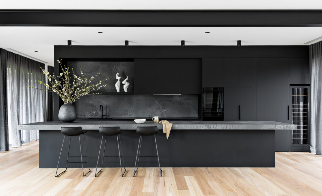 Minimalist black kitchen with timber floors, large Caesarstone<sup>®</sup> island bench, and integrated cabinetry.
