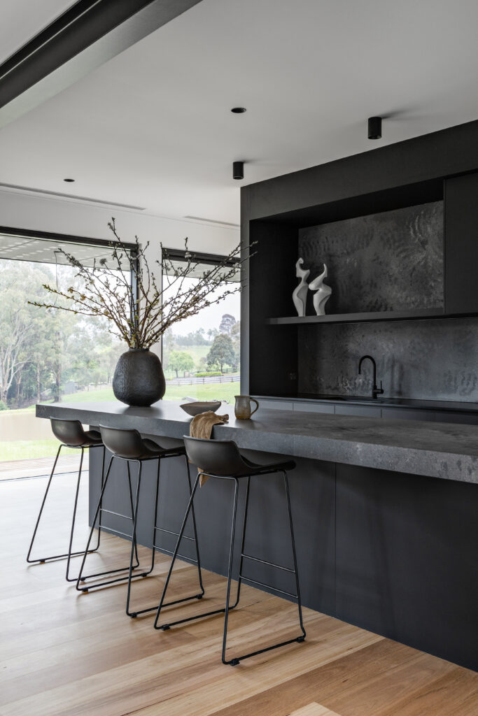 Black kitchen island bench with integrated seating and minimalist open shelving