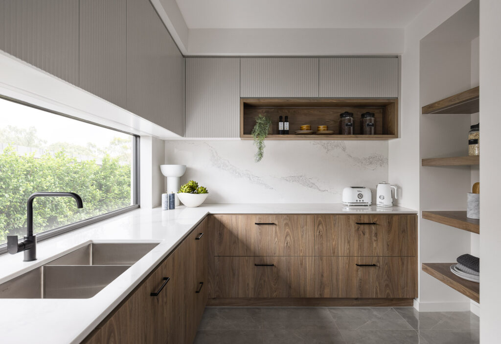Modern butler’s pantry with Caesarstone<sup>®</sup> benchtop and splashback, timber cabinetry, matte black tapware, and open shelving. 