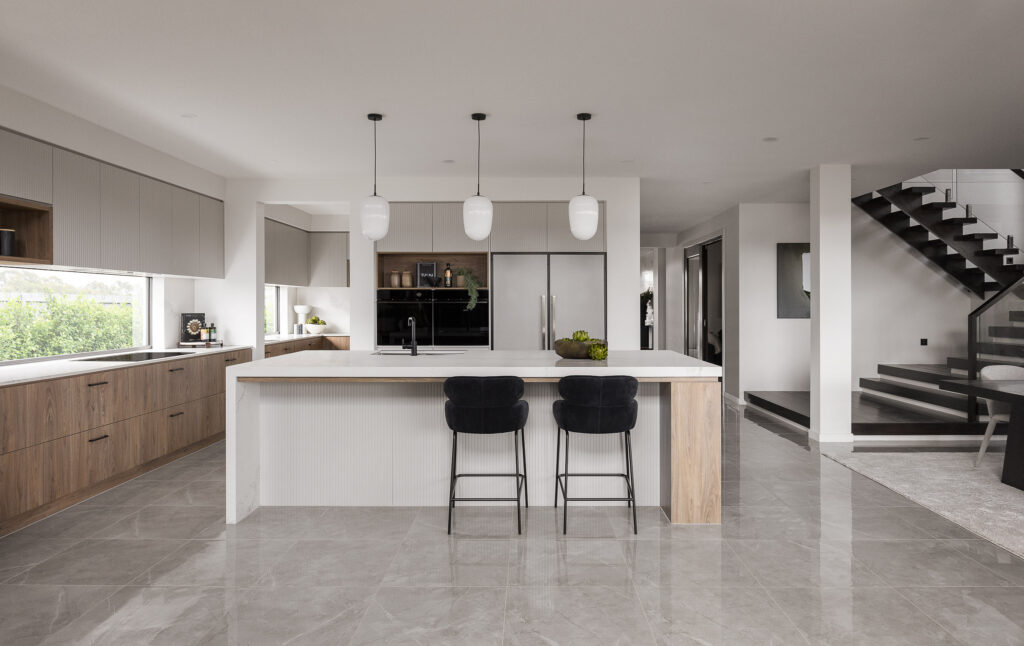 Sleek modern kitchen with Caesarstone<sup>®</sup> island bench, pendant lighting, timber and grey cabinetry, and large format tiled flooring.