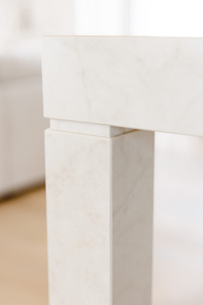 Close-up of Caesarstone<sup>®</sup> Marbannova custom leg detail on kitchen island., showing seamless joinery and sculptural support.  