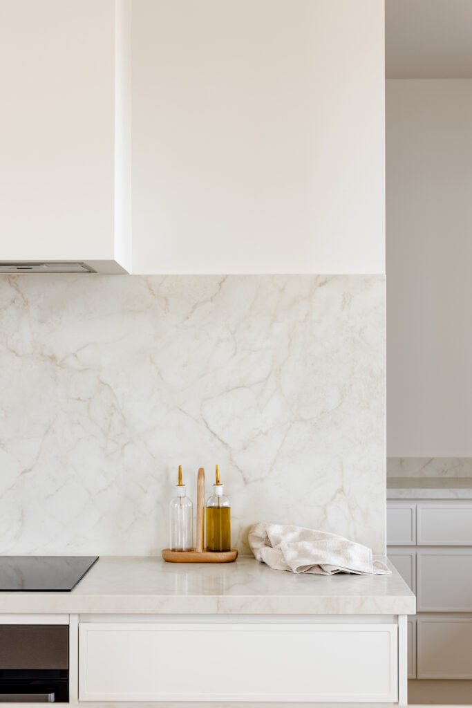 Detail of Caesarstone<sup>®</sup> benchtop and splashback with glass oil and vinegar bottles on a timber caddy.