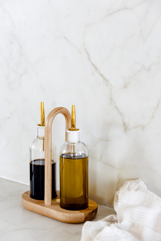 Detail of Caesarstone<sup>®</sup> benchtop and splashback with glass oil and vinegar bottles on a timber caddy.
