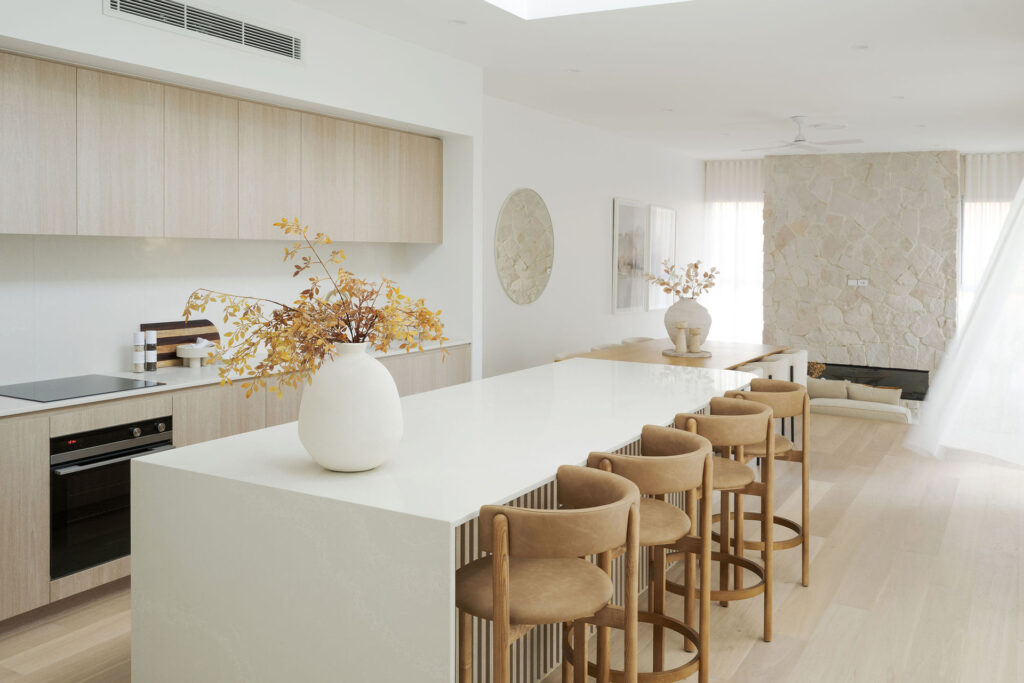 Bright kitchen with ribbed timber island, Caesarstone<sup>®</sup> benchtop, and skylight void filling the space with natural light.