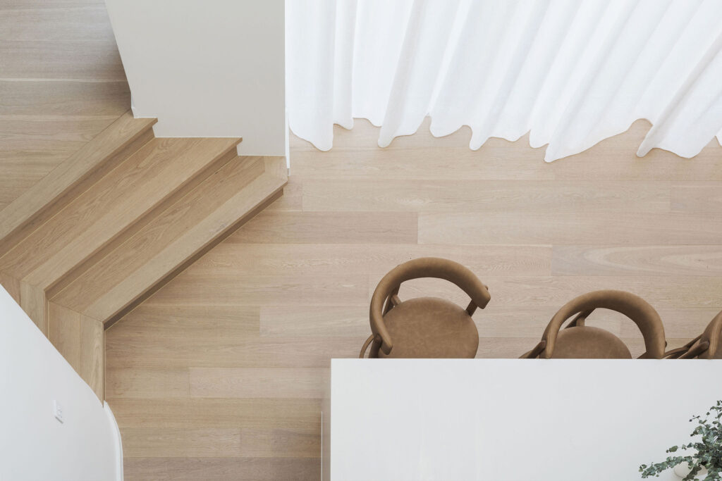 Overhead view of timber steps, bar stools, and a kitchen island with Caesarstone<sup>®</sup> benchtop in a coastal interior