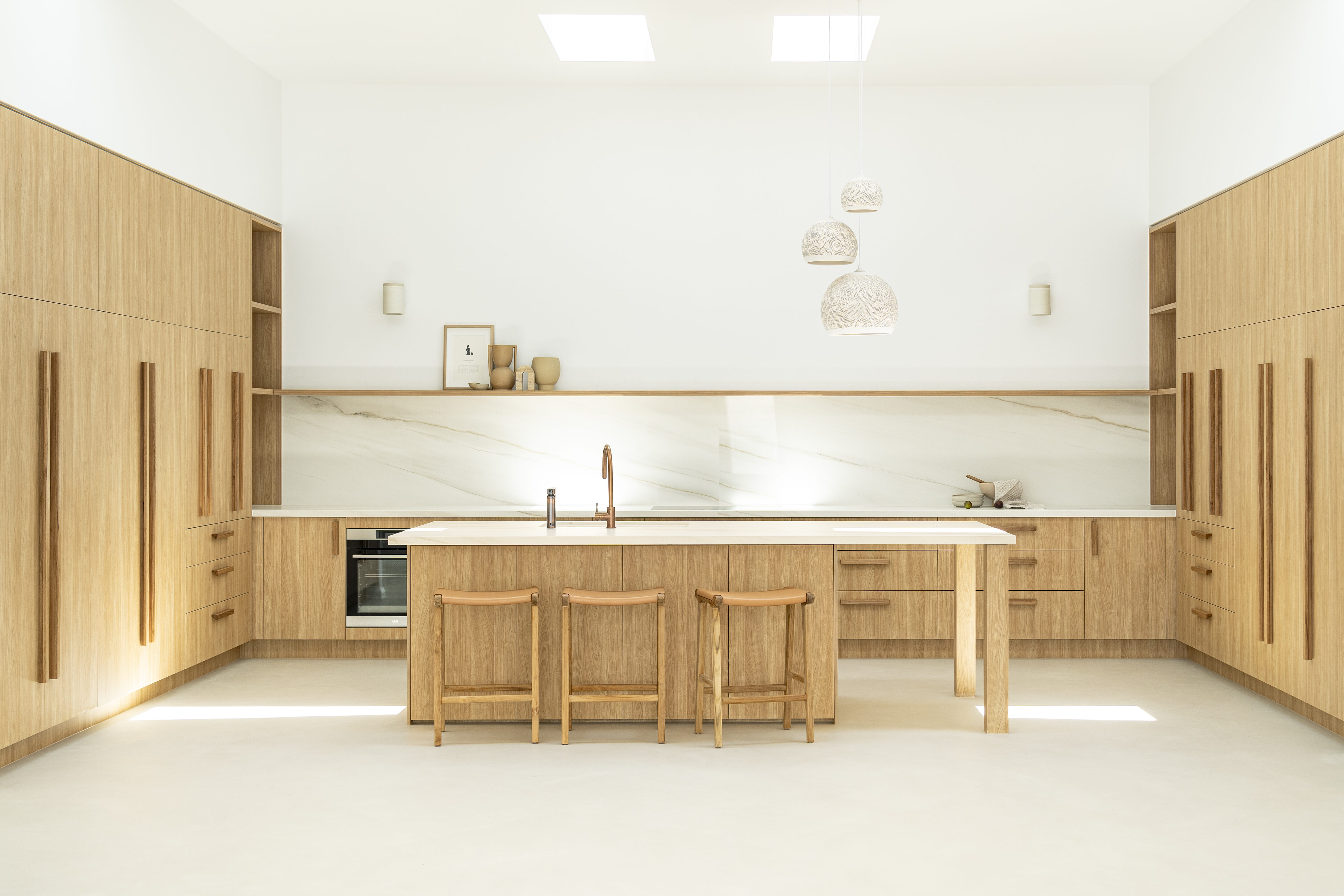 U-shaped kitchen design with Caesarstone Porcelain Sleet benchtops, island and splashback with brush fittings and warm timber joinery.