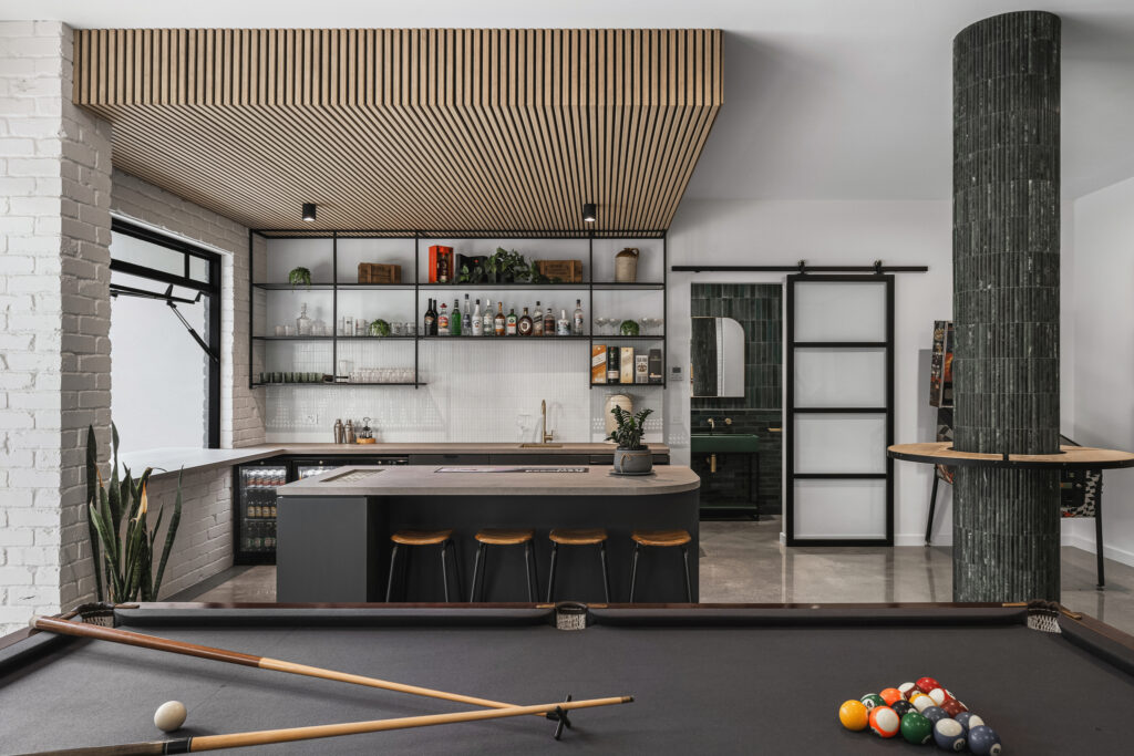 Entertainer’s bar with Caesarstone<sup>®</sup> Porcelain benchtop, timber slatted ceiling, open shelving, and pool table.
