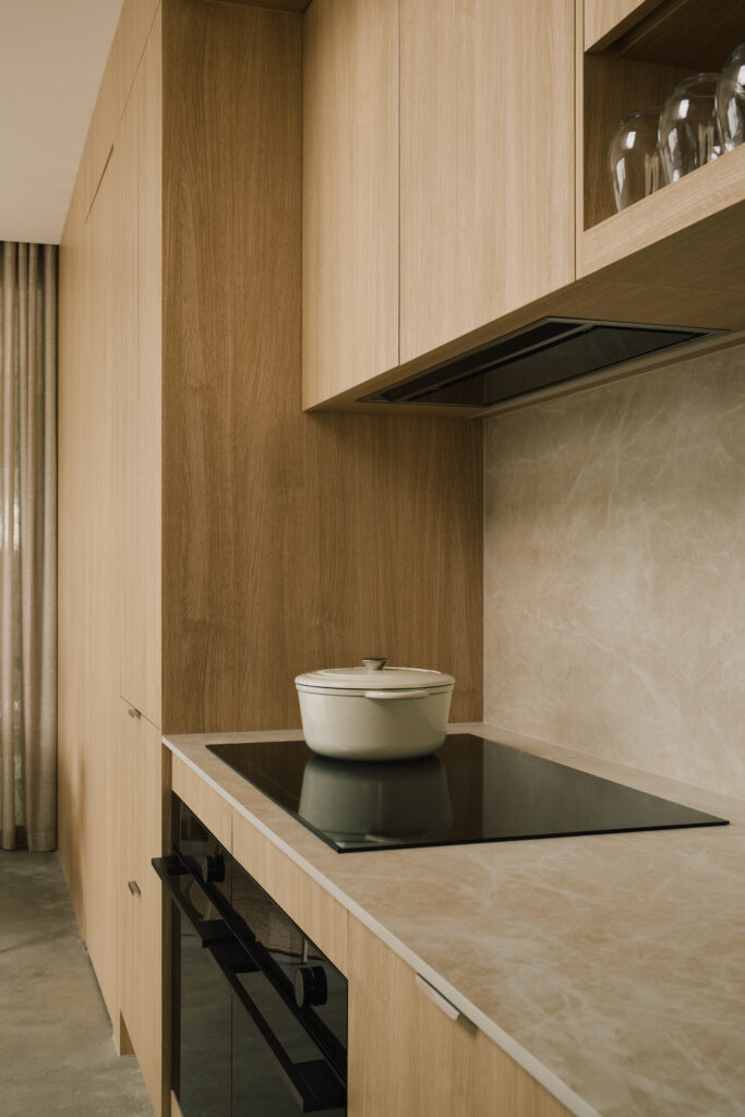 Kitchen detail featuring Caesarstone<sup>®</sup> Porcelain benchtop and splashback with warm oak cabinetry.