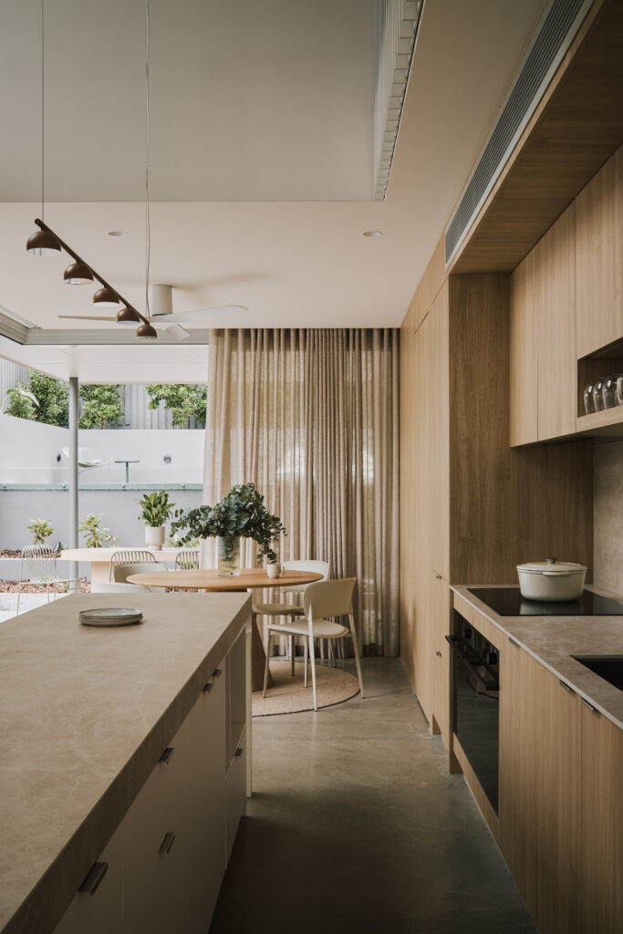 Open-plan kitchen and dining space featuring Caesarstone<sup>®</sup> Porcelain island benchtop and timber joinery with soft natural light.