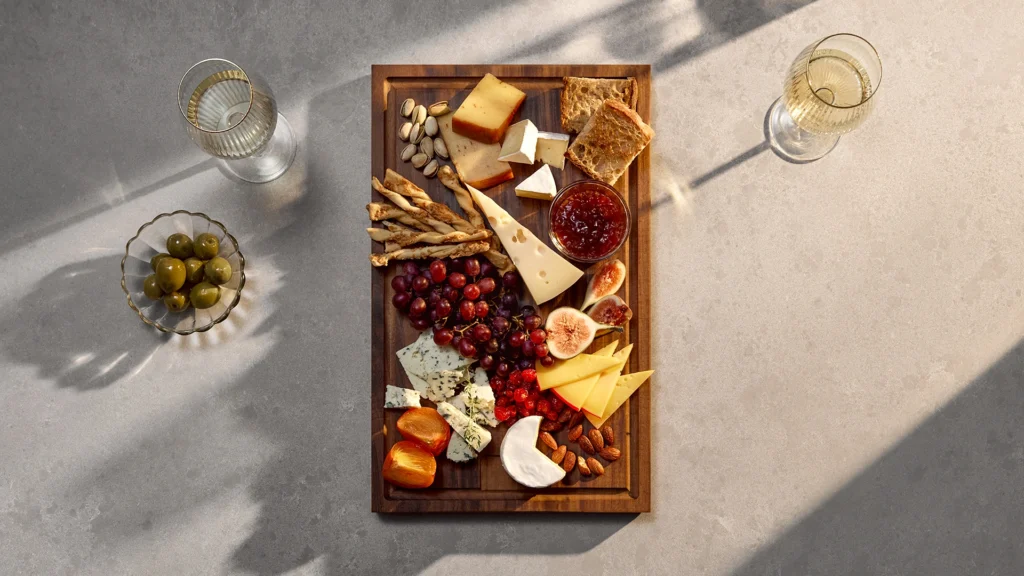 Caesarstone Airy Concrete Mineral surface styled with a cheese board and wine, highlighting its durability for any occasion.