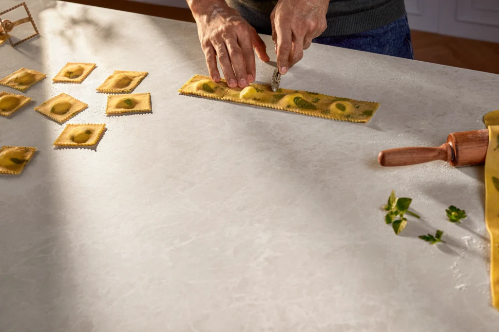 Making fresh ravioli on Caesarstone Lucillia Porcelain benchtop, showing its smooth, durable cooking surface.