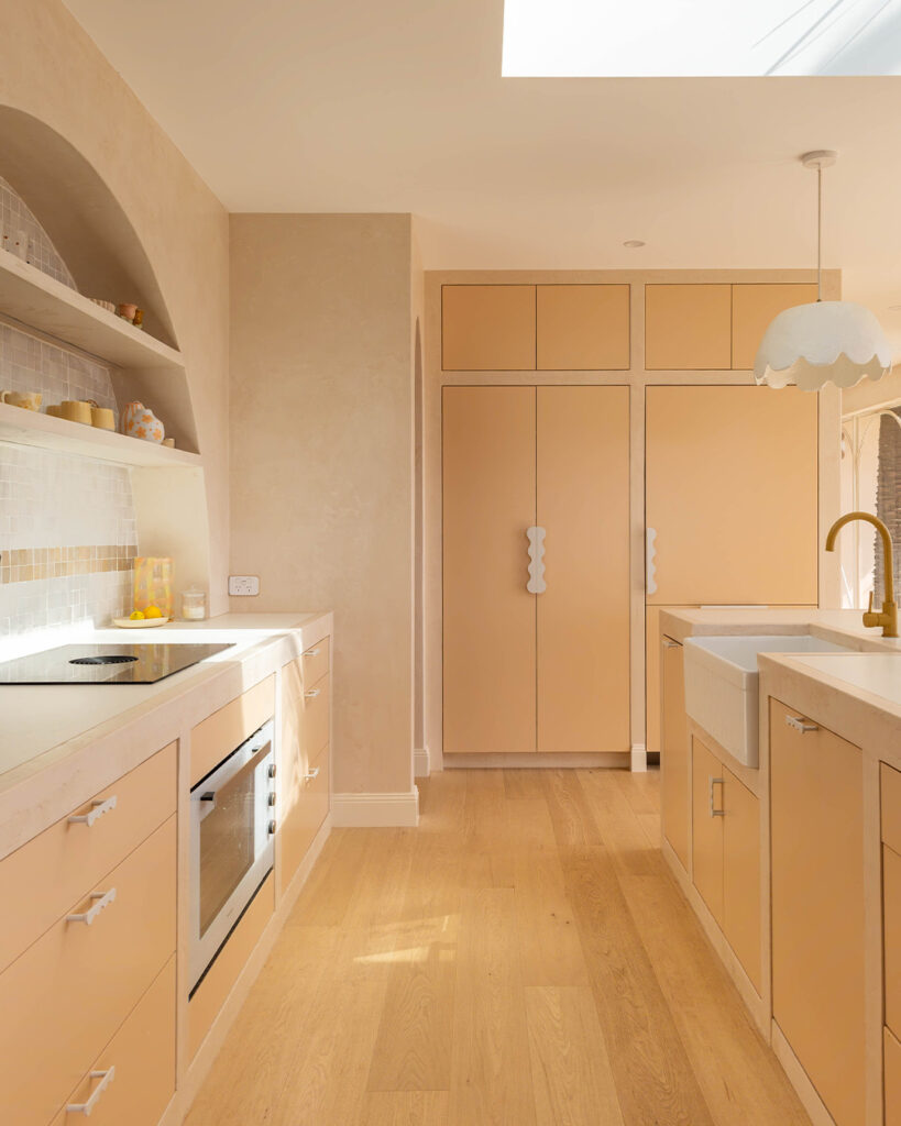 Light-filled contemporary kitchen featuring Caesarstone<sup>®</sup> Porcelain White Ciment benchtops, with warm neutral cabinetry, integrated appliances, and a modern Australian interior design aesthetic.