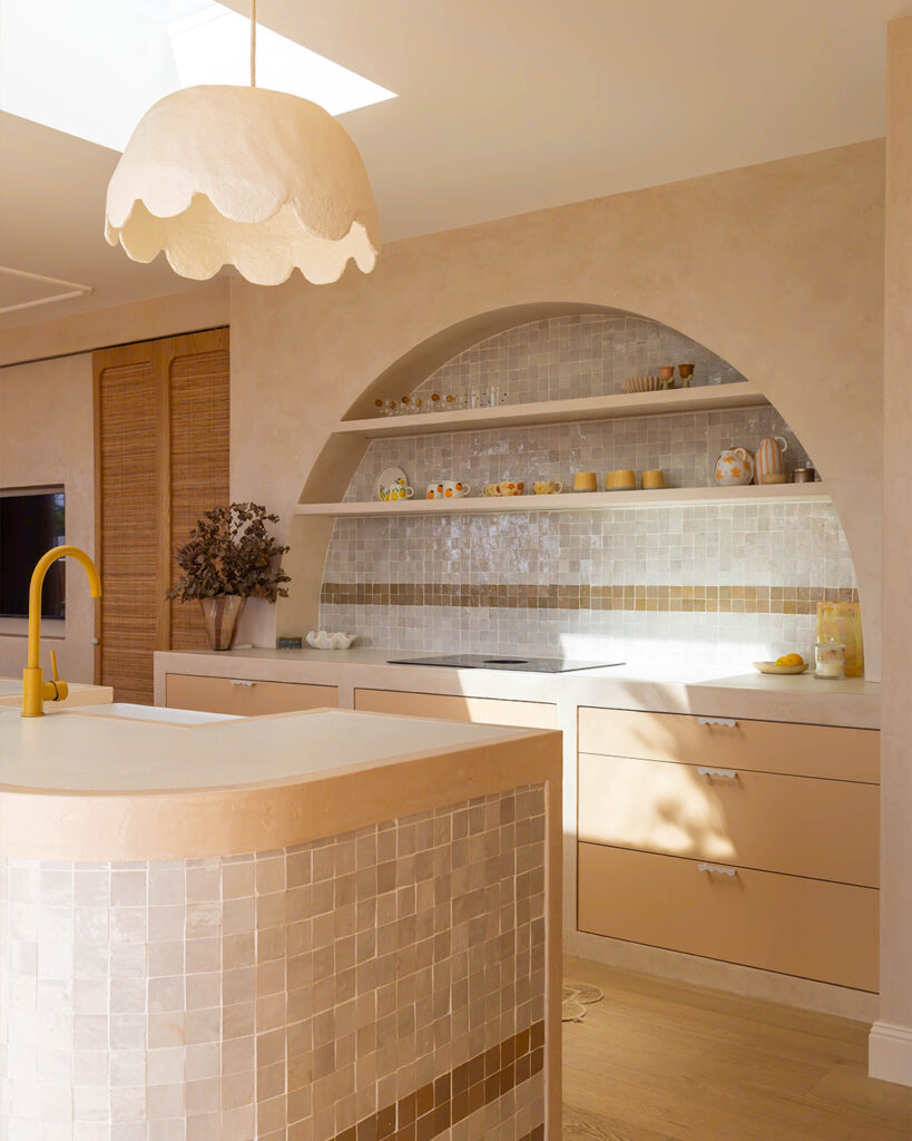 Curved kitchen island with mosaic tile finish and arched shelving in warm neutral kitchen made with porcelain benchtops.