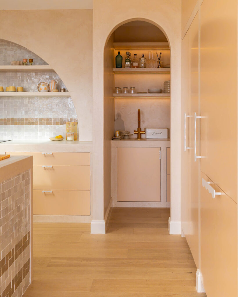 Arched pantry nook with open shelving and concealed storage in neutral kitchen