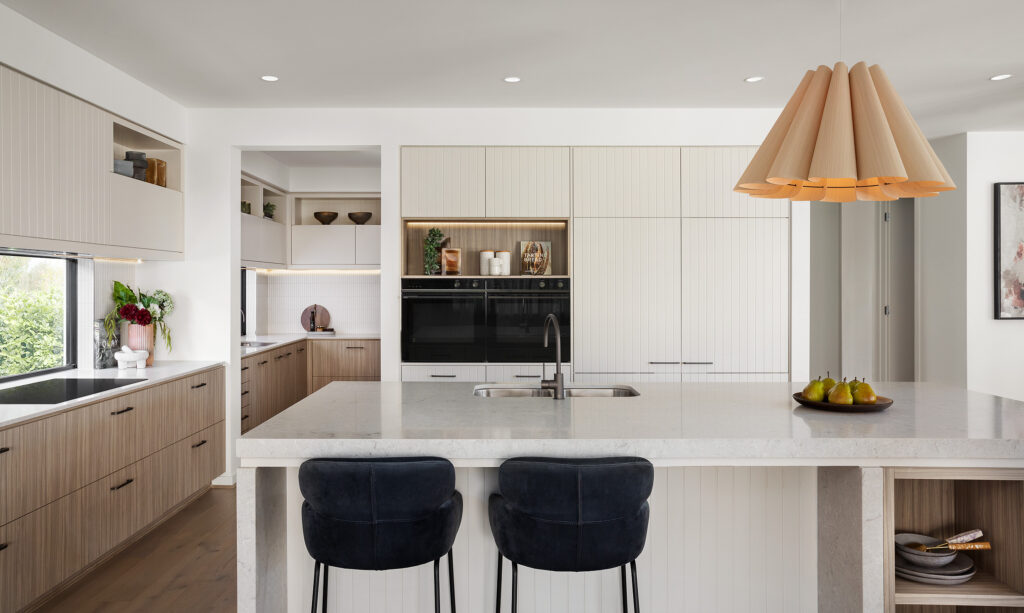 Kitchen island and butler’s pantry with Bianco Drift surfaces at Carlisle Homes Rothbury Grand Atrium