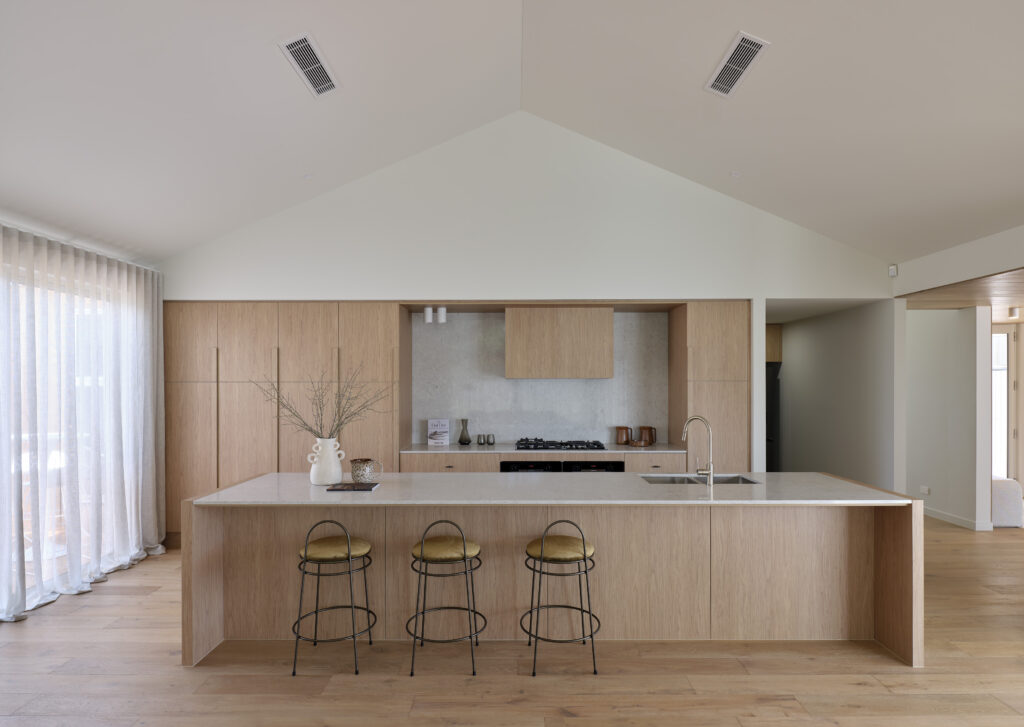 Kitchen with Bianco Drift benchtop and warm timber cabinetry by Roseleigh Homes