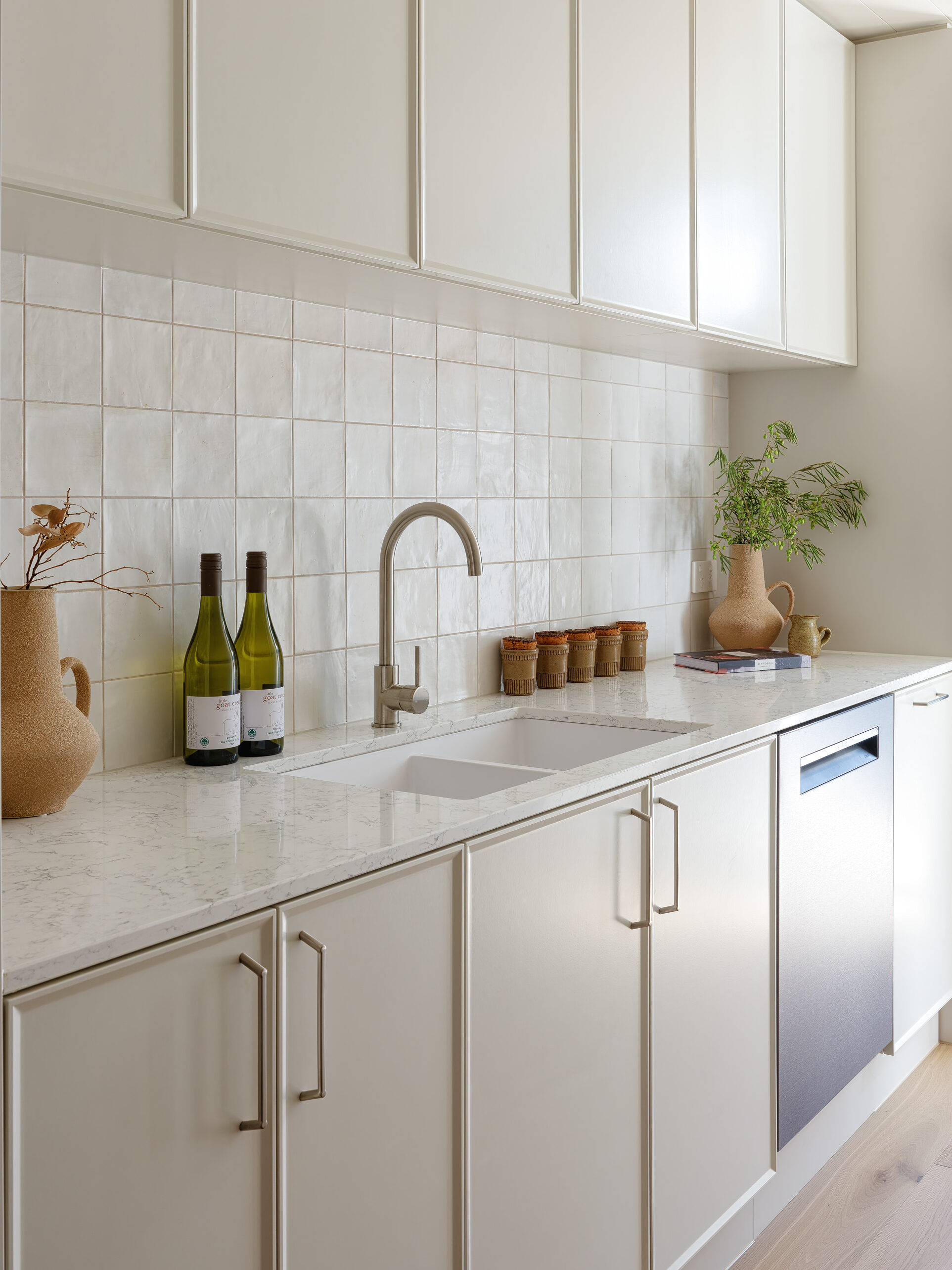 Kitchen benchtop and sink in Caesarstone Arabetto™ with tiled splashback, neutral cabinetry, and timber flooring