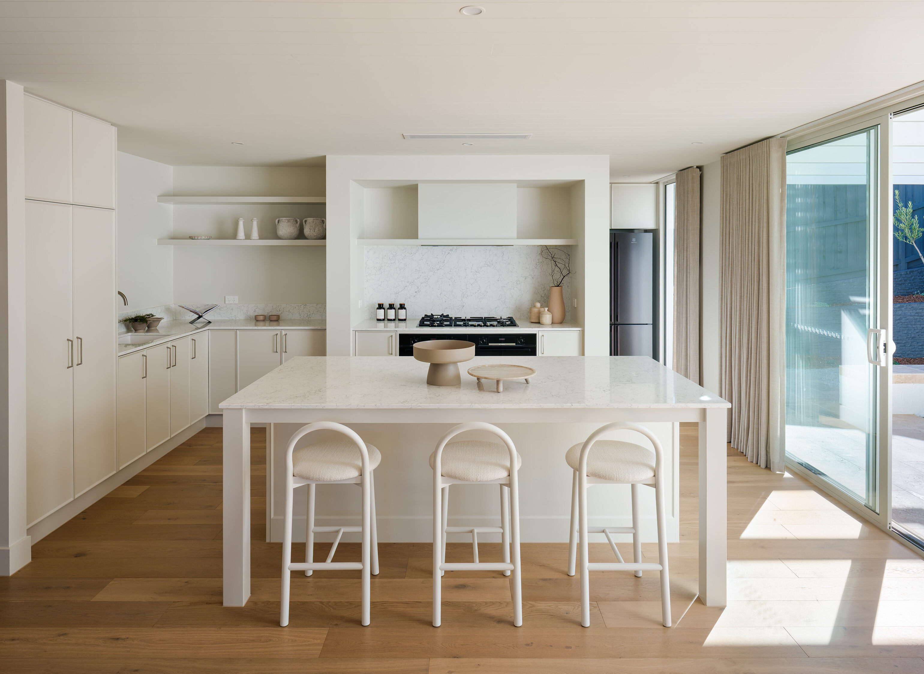 Open plan kitchen with Caesarstone Arabetto™ mineral benchtop, timber flooring, vaulted ceiling, and natural light at The Alma display home