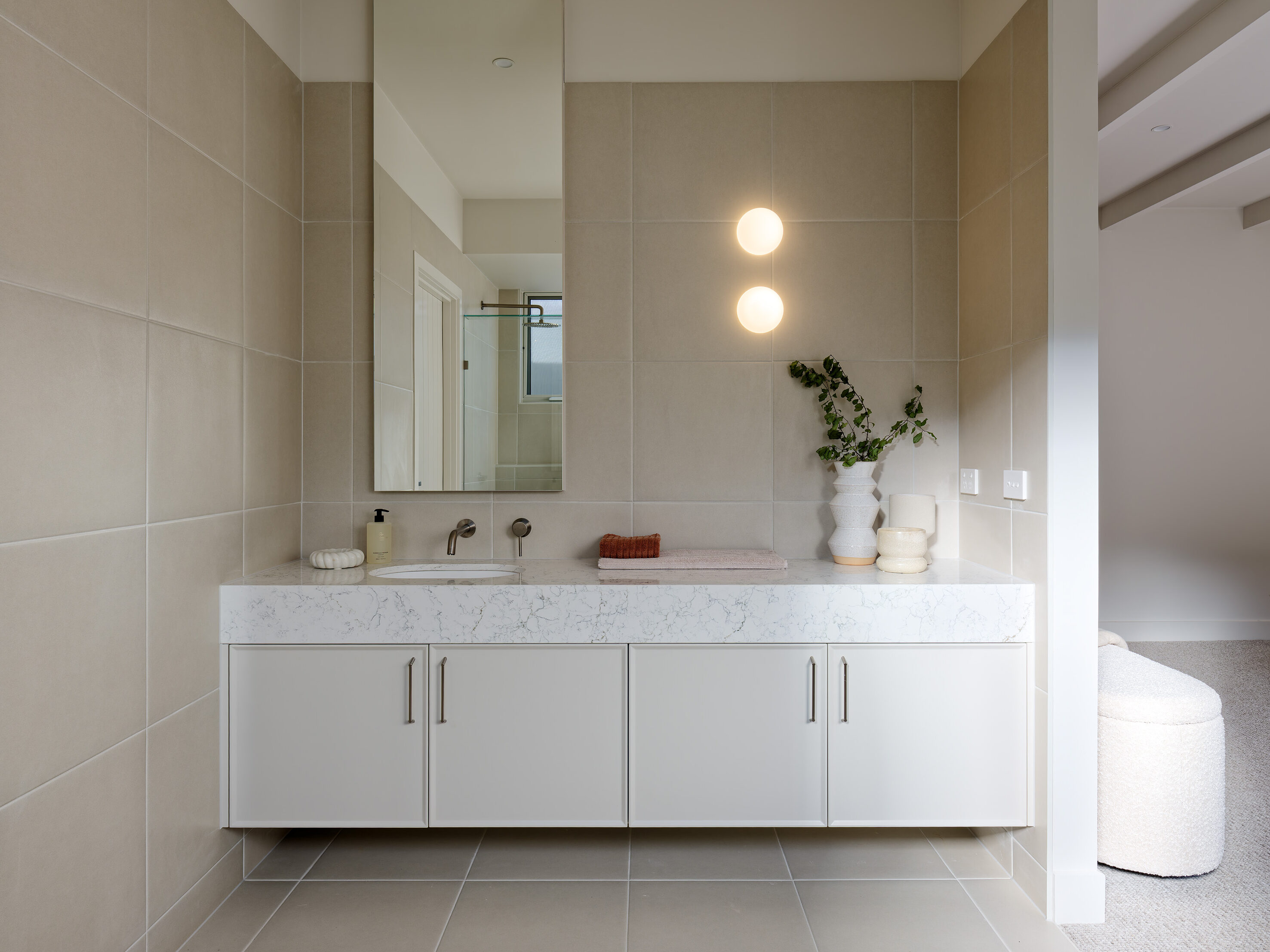 Bathroom vanity with Caesarstone Arabetto™ mineral benchtop, soft beige tiles, and minimalist cabinetry