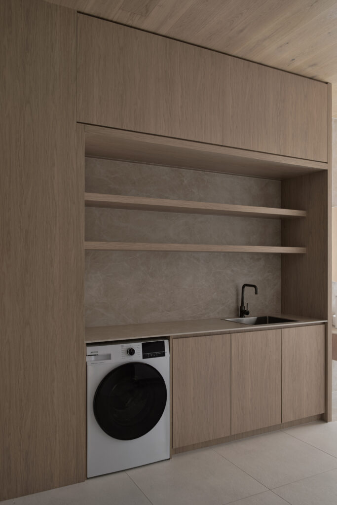 Laundry display inside Caesarstone’s Wingfield showroom in Adelaide featuring Caesarstone<sup>®</sup> Porcelain™ Fume surfaces with integrated timber cabinetry.