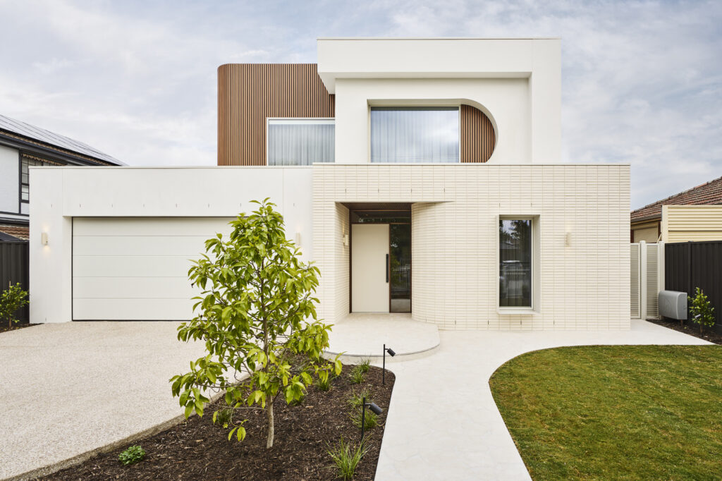 Contemporary home exterior with curved architectural facade and light brick cladding at The Kingscliff, Melbourne inner north west.
