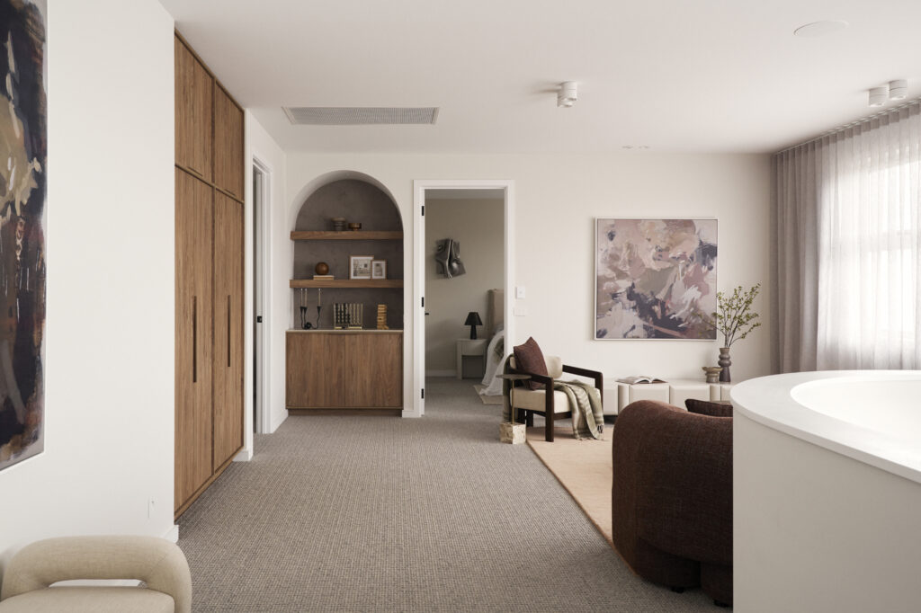 Living area with built-in timber cabinetry, curved shelving niche and soft neutral furnishings at The Kingscliff, Melbourne