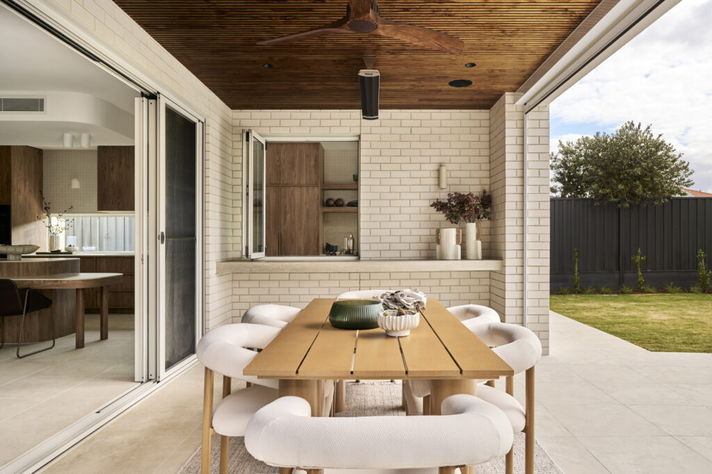 Outdoor alfresco dining area with timber ceiling, sliding doors and landscaped backyard at The Kingscliff, Melbourne