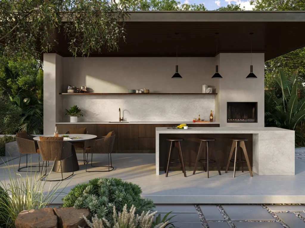 Caesarstone<sup>®</sup> Crestone pale concrete-look benchtop on freestanding outdoor kitchen island with pendant lighting and rattan bar stools in landscaped Australian alfresco space