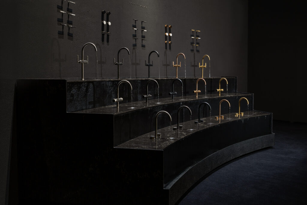 Close-up of GROHE SPA tapware in multiple finishes set against Caesarstone<sup>®</sup> surfaces, highlighting the interplay of material, reflection and flowing water.