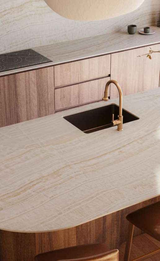 Caesarstone<sup>®</sup> Onyxa™ 509 porcelain curved kitchen island benchtop with brass tapware and timber cabinetry