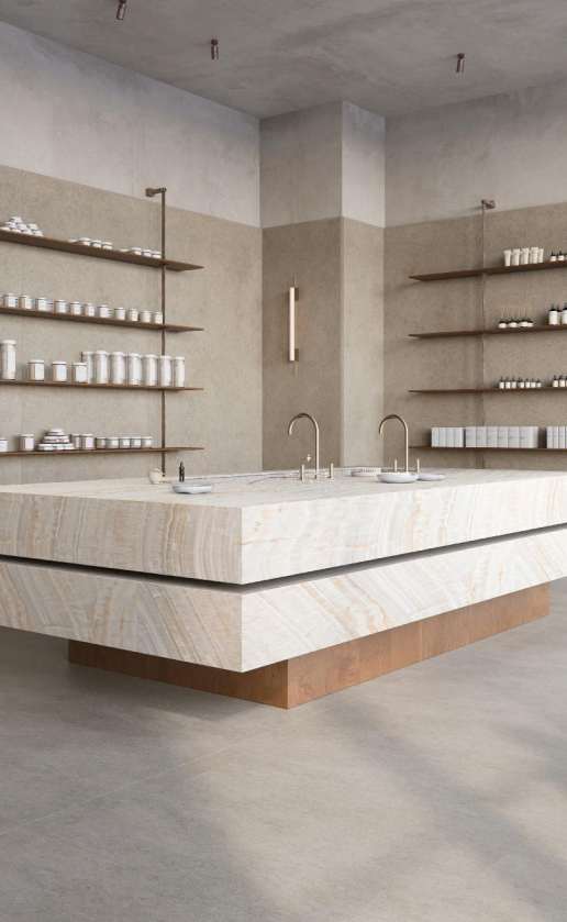 Caesarstone<sup>®</sup> Onyxa™ 509 porcelain island benchtop in minimalist retail or commercial interior with shelving and concrete flooring