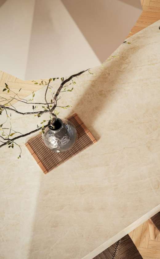 Caesarstone<sup>®</sup> Opal Taj™ 584 porcelain benchtop detail with earthy neutral veining, ceramic vase and branch styling in warm interior