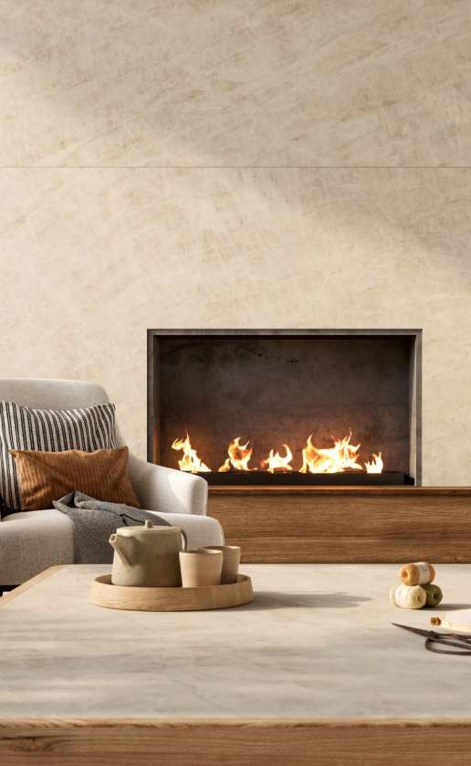Caesarstone<sup>®</sup> Opal Taj™ 584 porcelain feature wall surface beside linear gas fireplace in warm living room with timber accents and soft furnishings