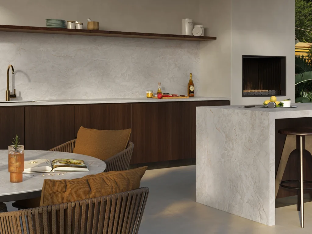 Warm concrete-aesthetic Caesarstone<sup>®</sup> surface running across a kitchen island and fireplace surround in an open-plan living space with timber joinery and earthy styling.